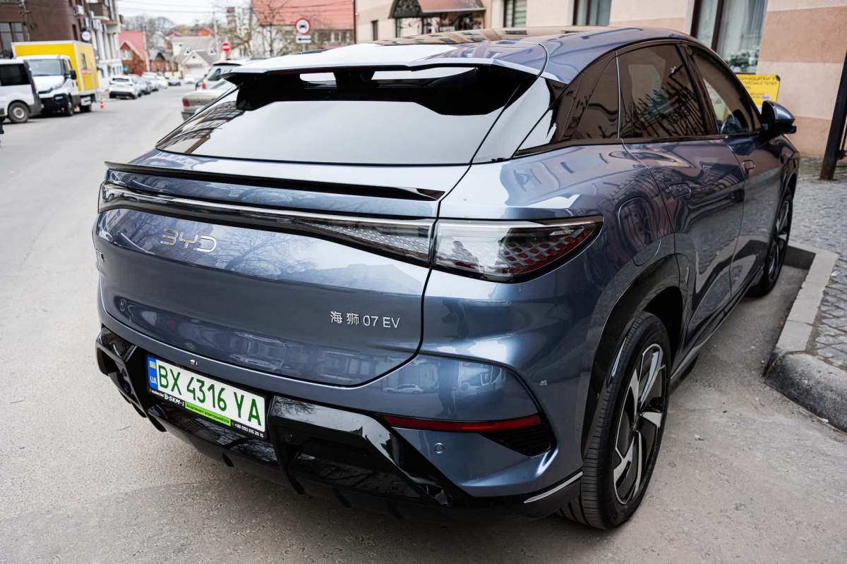 A blue electric SUV parked on a city street with a visible license plate.