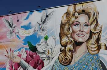 A mural depicting Dolly Parton surrounded by flowers and doves