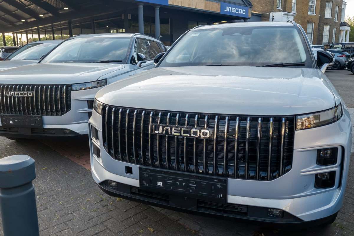 Two silver SUVs with prominent grilles parked in front of a dealership.