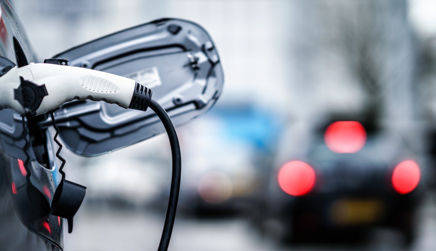 An electric car charging cable connected to a parked vehicle.