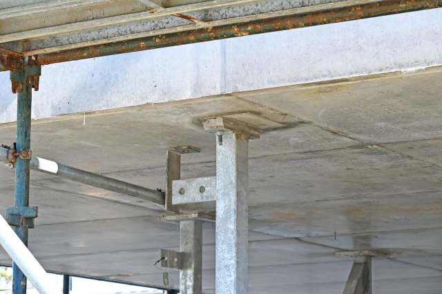 A view of scaffolding supports and a concrete slab from below.