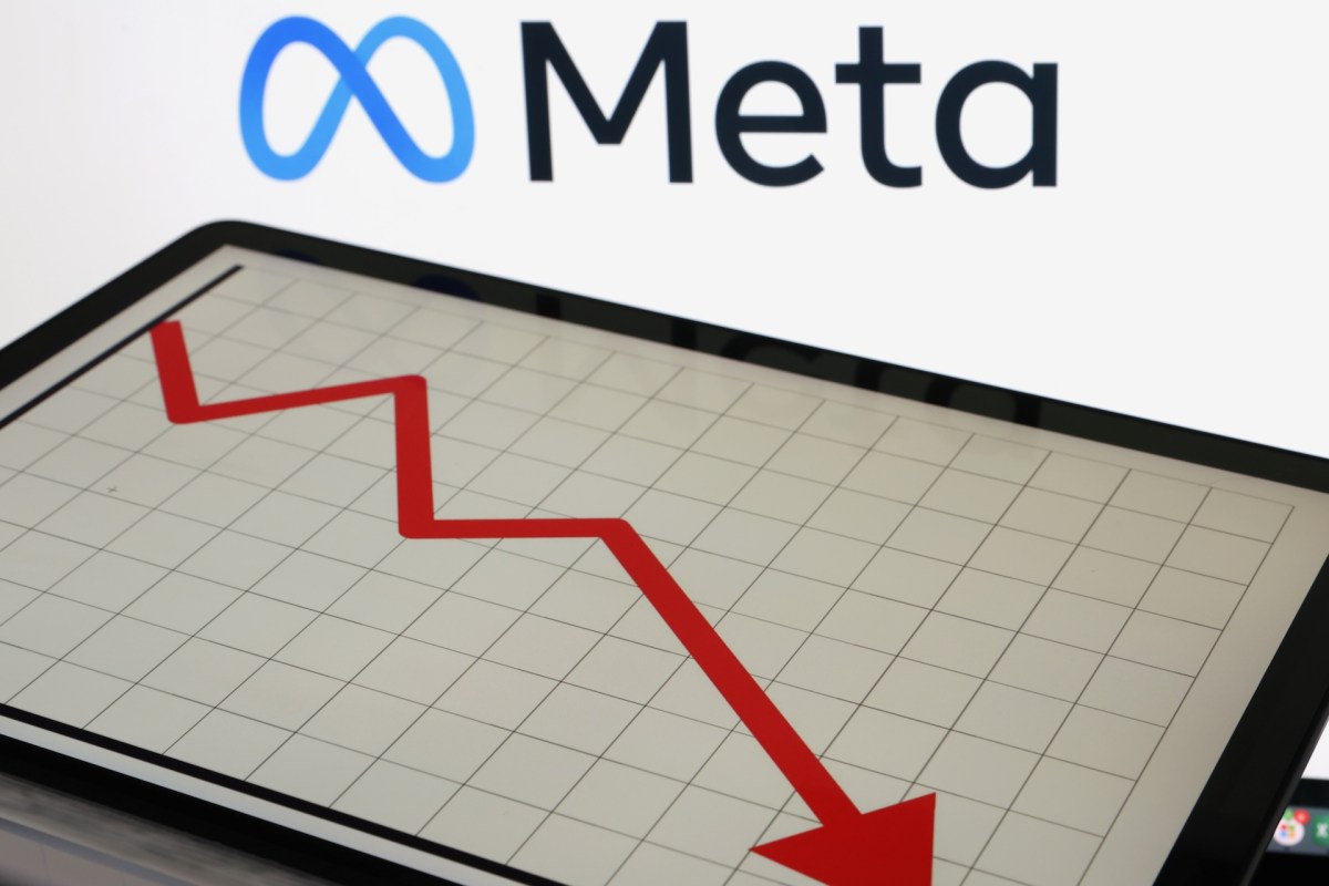 A tablet displaying a red downward trend graph in front of the Meta logo.