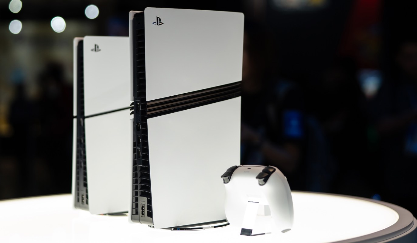 A white gaming console and controller displayed on a circular stand.