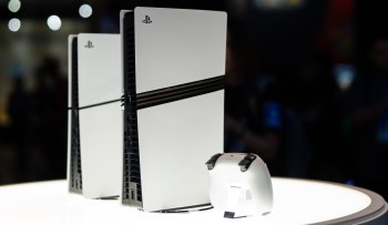 A white gaming console and controller displayed on a circular stand.