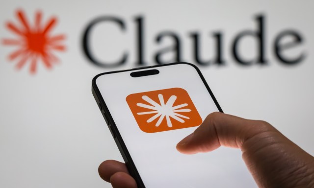 A hand holds a smartphone displaying an orange app icon, with "Claude" logo in the background.