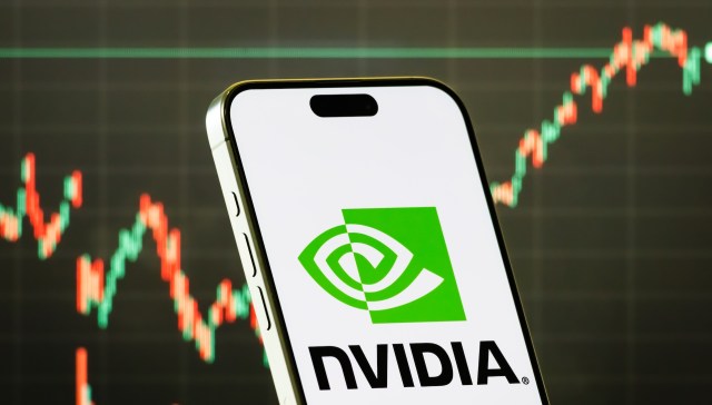 A smartphone displaying the NVIDIA logo with a stock market chart in the background.