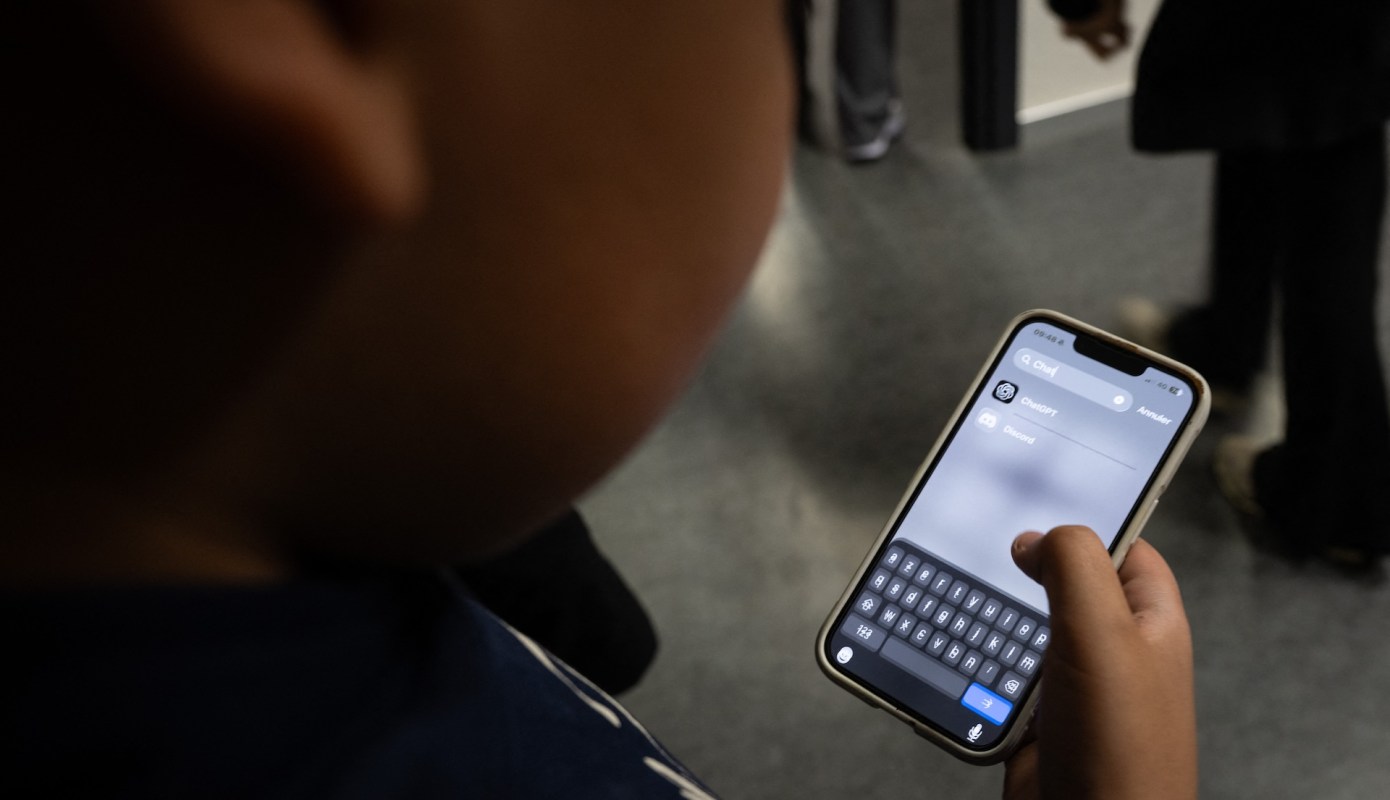 A young person using a smartphone with a ChatGPT application open on the screen.
