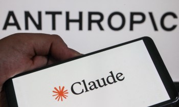 A hand holds a smartphone displaying the logo "Claude" in front of a background with the word "ANTHROPIC."