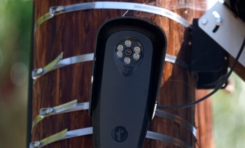 A Flock Safety surveillance camera mounted on a wooden utility pole with metal straps.