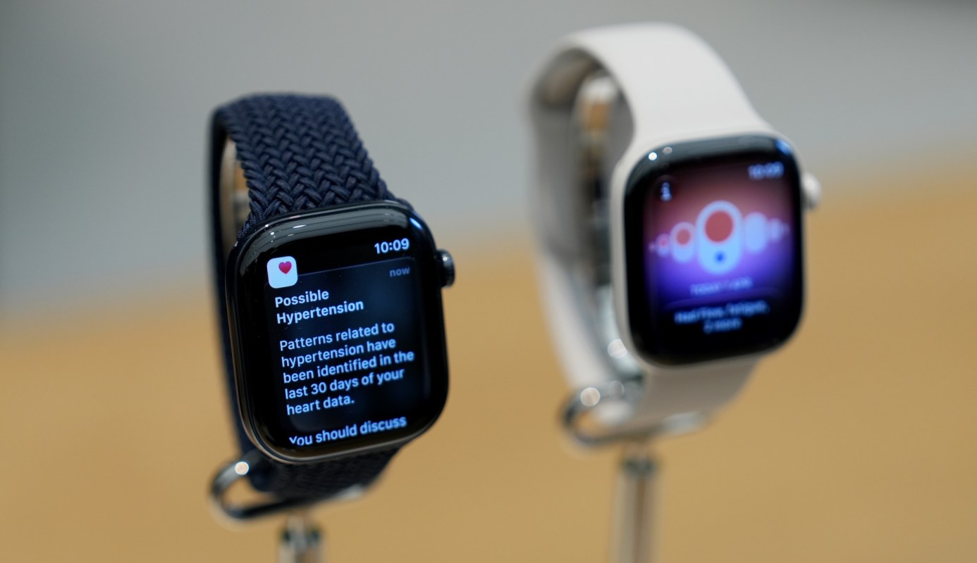 Two Apple Watch Series 12 displaying health notifications on their screens, one with a navy strap and the other white.