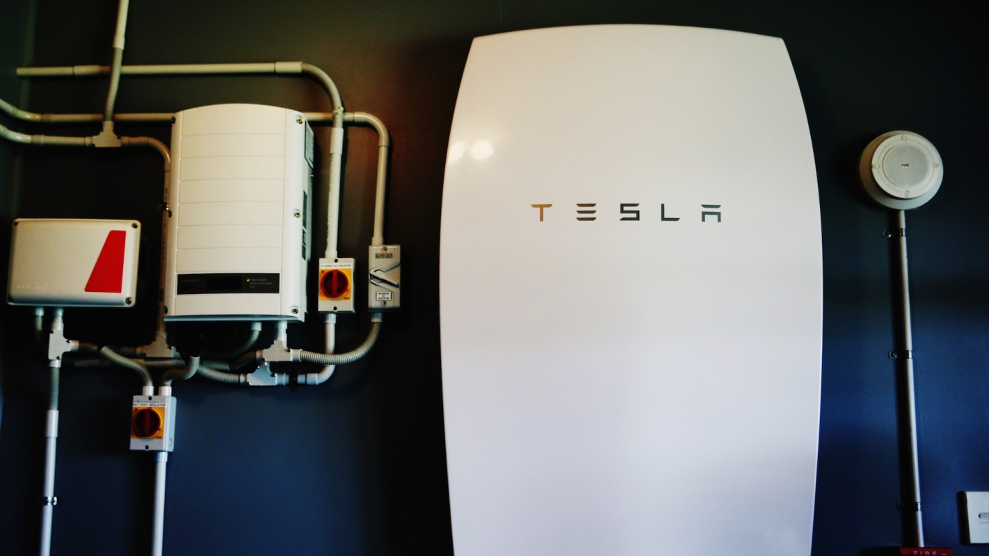 A Tesla Powerwall unit with electrical components mounted on a wall.