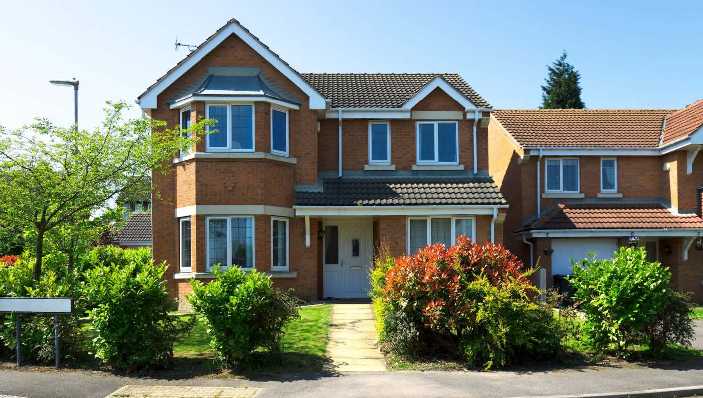 A two-story brick house with a garden.