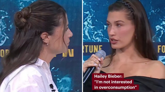 Two women facing each other during an interview, one holding a microphone and speaking.