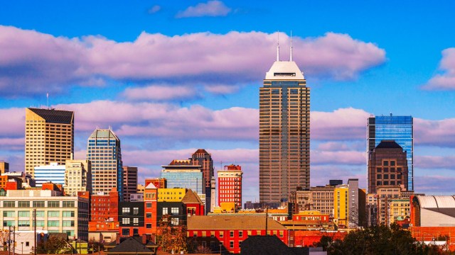 A Indianapolis skyline view of urban buildings against a blue sky with clouds.
