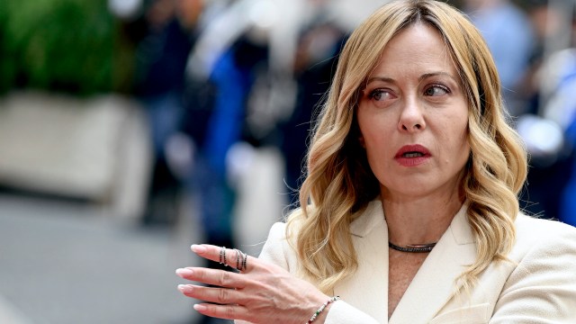 Italy prime minister Giorgia Meloni gestures while speaking in a crowded outdoor setting.