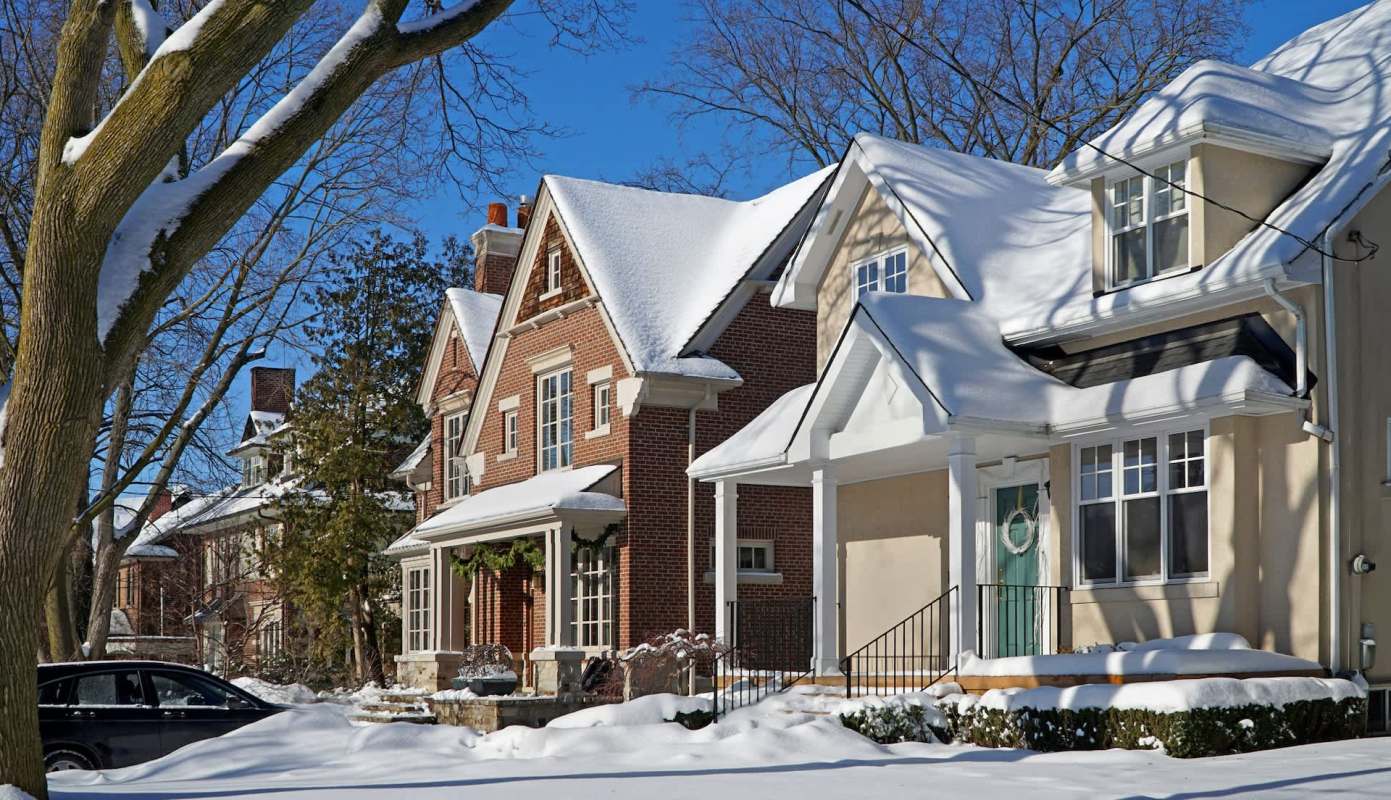 A row of houses covered in snow under a clear blue sky.