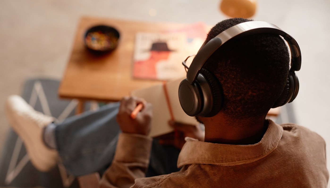 A person wearing headphones and writing.