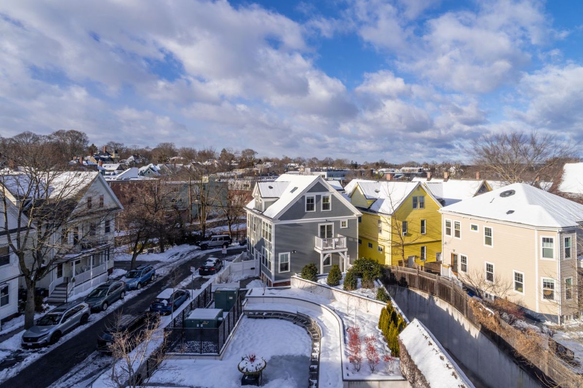 A view of residential buildings covered in snow under a partly cloudy sky in Massachusetts
