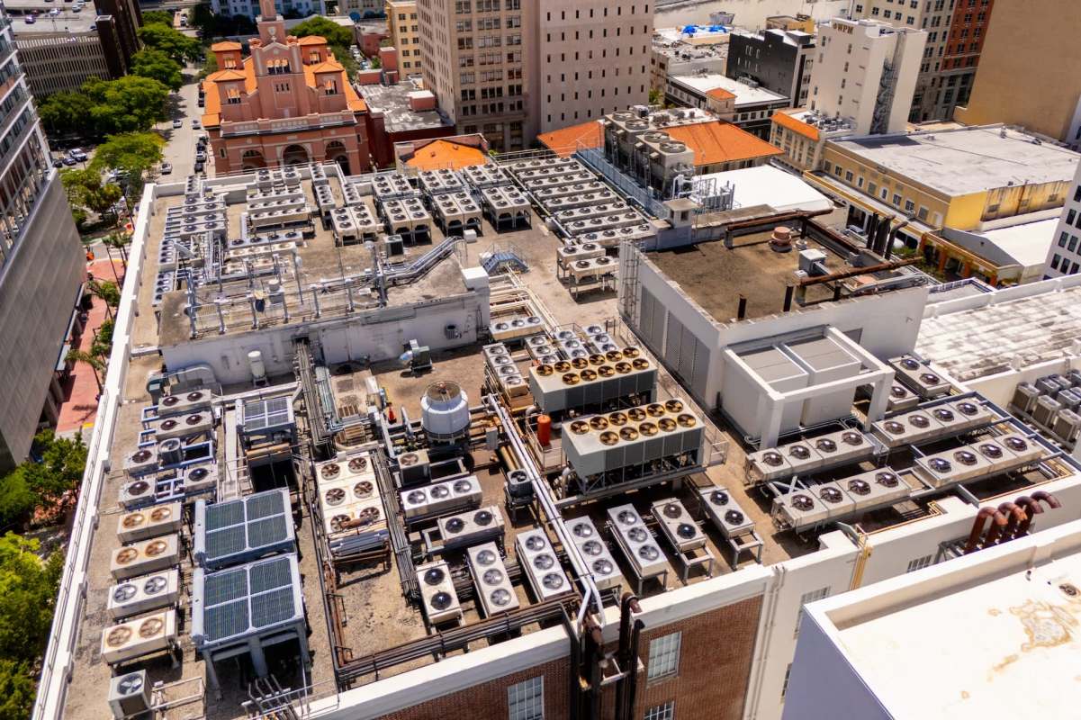 An industrial rooftop in Miami with numerous air conditioning units and solar panels.