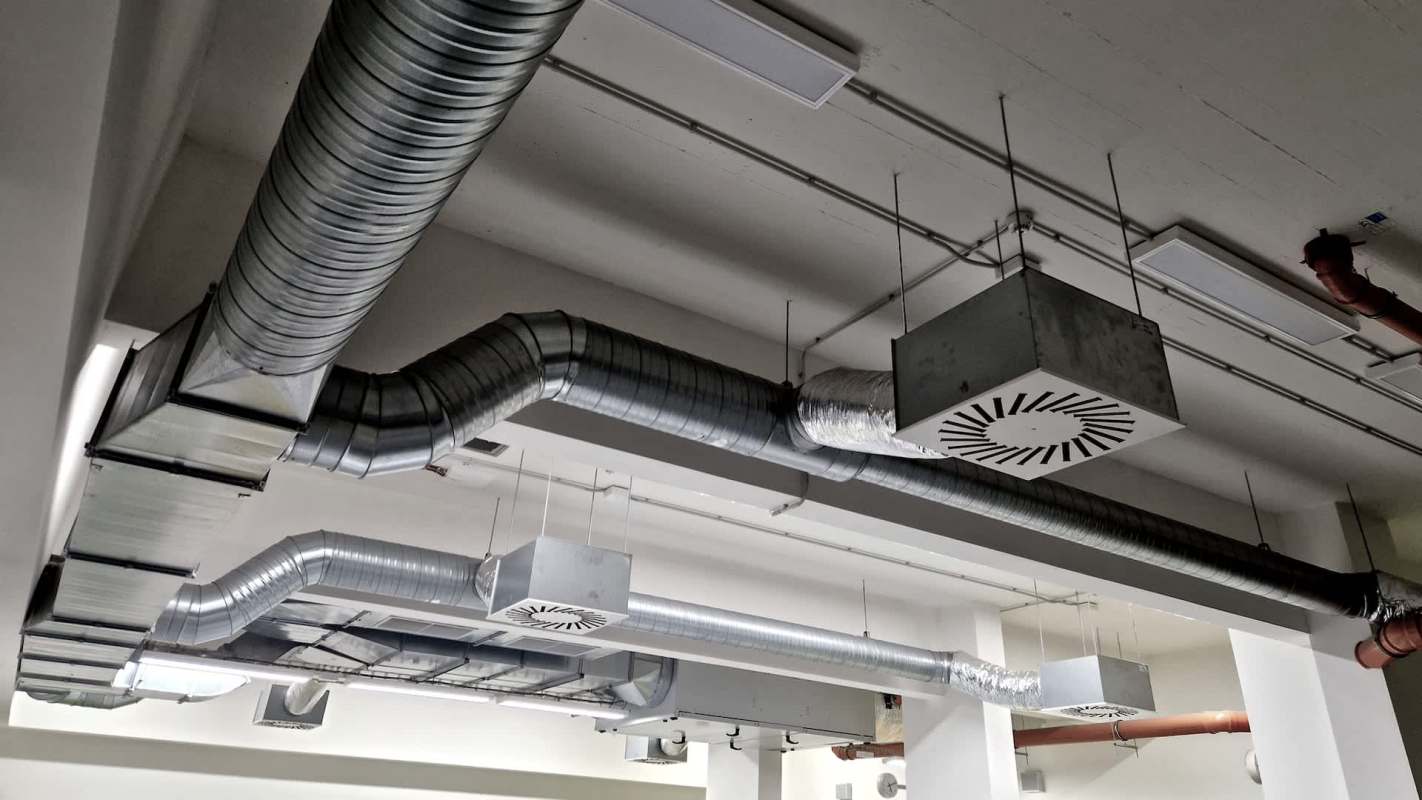 A ceiling featuring several metal ductwork and ventilation systems.