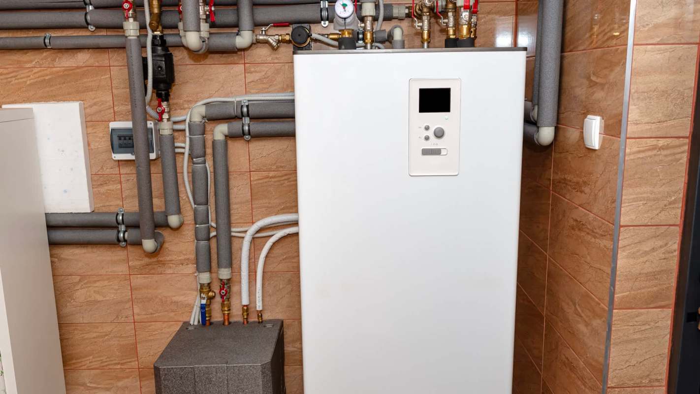 A heating system with various pipes and connections, set against a tiled wall.