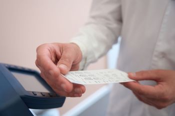 A person holding a receipt next to a digital display device.