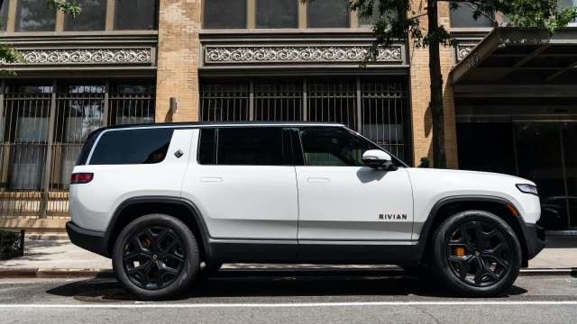 A white electric SUV parked on the street next to a brick building.