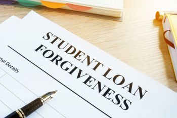 A paper application for student loan forgiveness sits on a desk with a pen