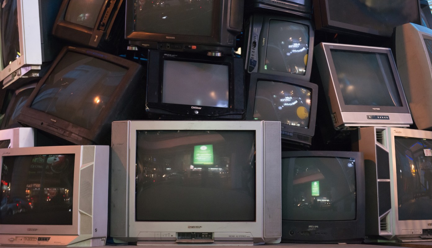 A stack of old television sets in various sizes and models.