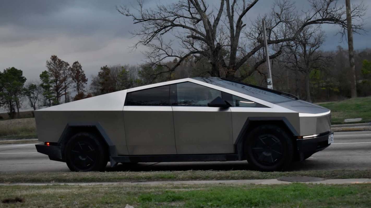 A futuristic electric vehicle parked on the side of a road with trees in the background.