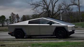 A futuristic electric vehicle parked on the side of a road with trees in the background.