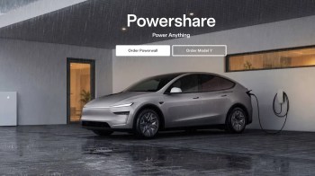 A silver Tesla charging outside a modern home during rain, with a Tesla Powerwall nearby.