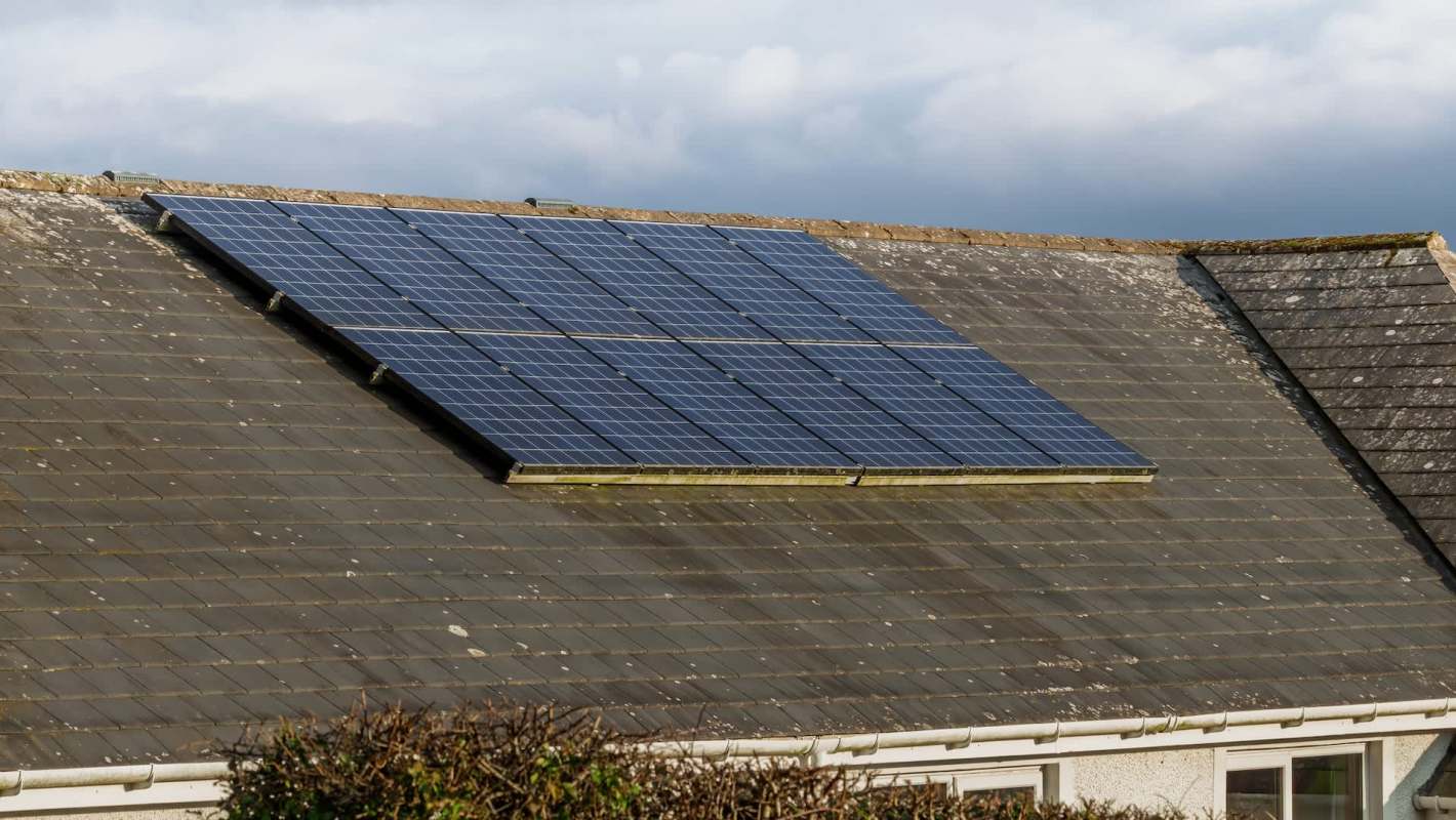 Solar panels installed on a sloped roof with weathered tiles.