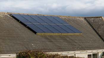 Solar panels installed on a sloped roof with weathered tiles.
