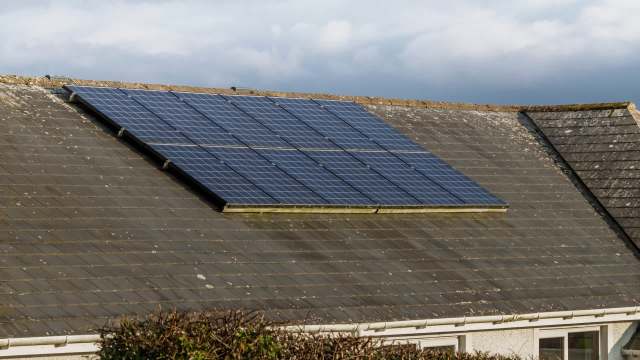 Solar panels installed on a sloped roof with weathered tiles.