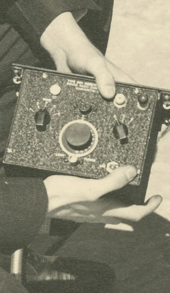 A grainy image of a person holding a radio.