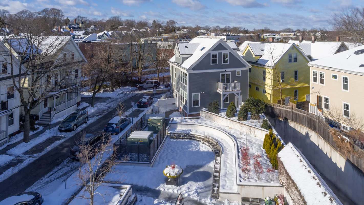 Aerial view of residential houses and snow-covered yards in an urban area.