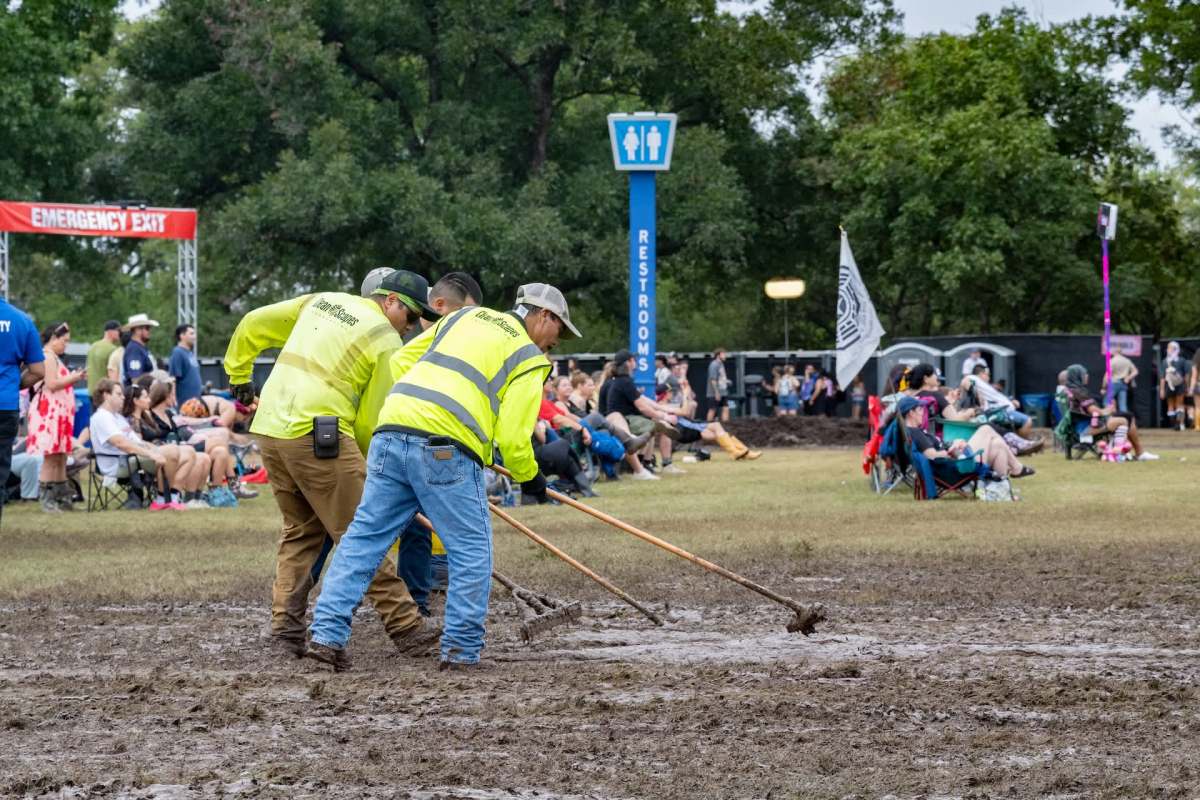 Workers raking mud at Austin City Limits.