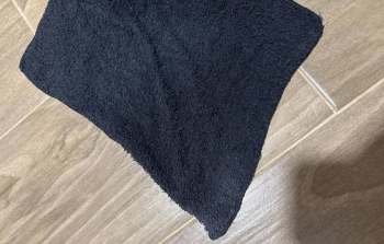 A dark towel laying on a wooden floor.