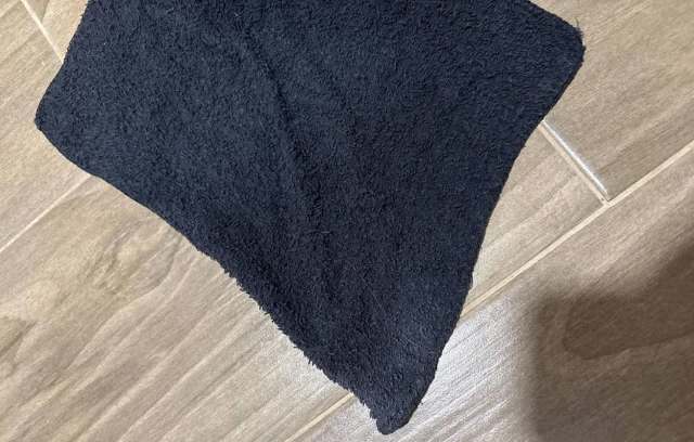 A dark towel laying on a wooden floor.