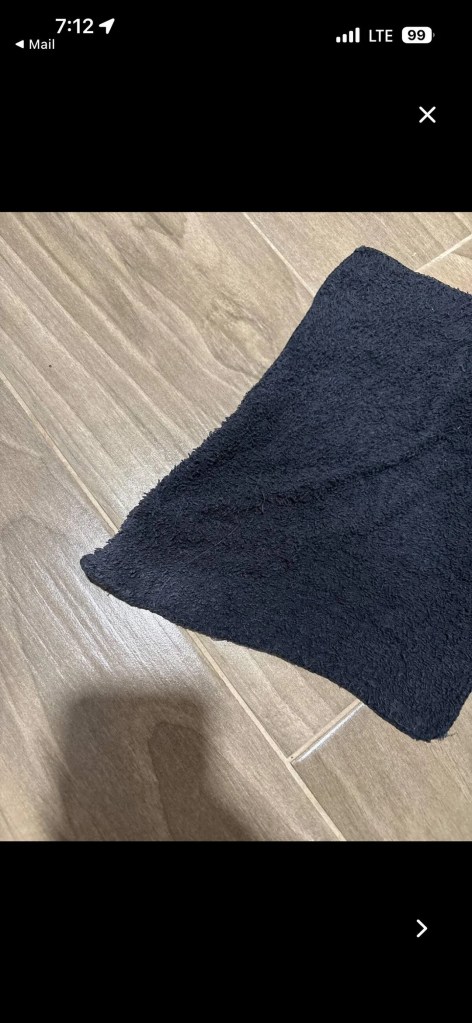 A dark towel laying on a wooden floor.