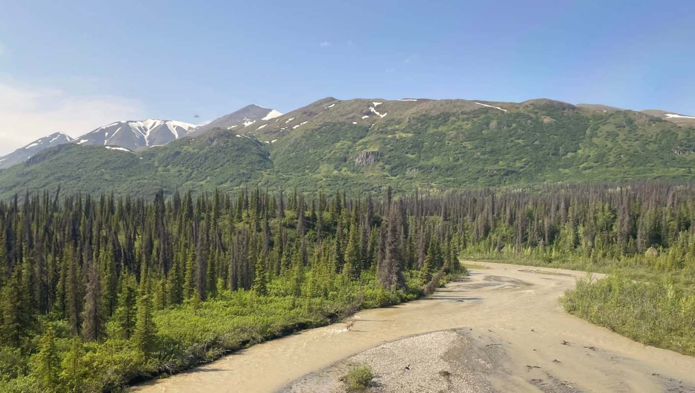 A river winds through a landscape of mountains and dense green forests.