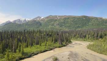 A river winds through a landscape of mountains and dense green forests.