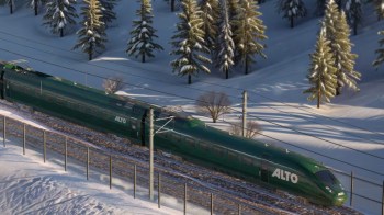 A green Alto train runs along snowy tracks surrounded by trees.