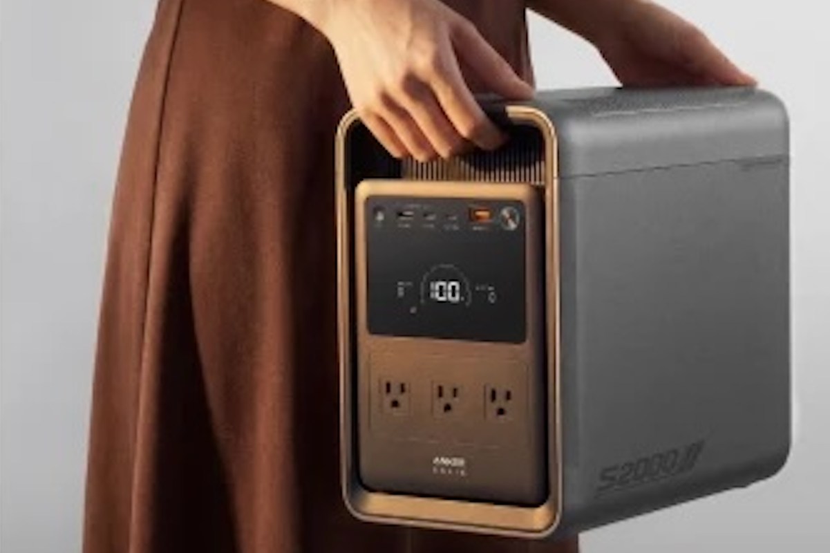 A person holding a portable power station with multiple outlets and a digital display.