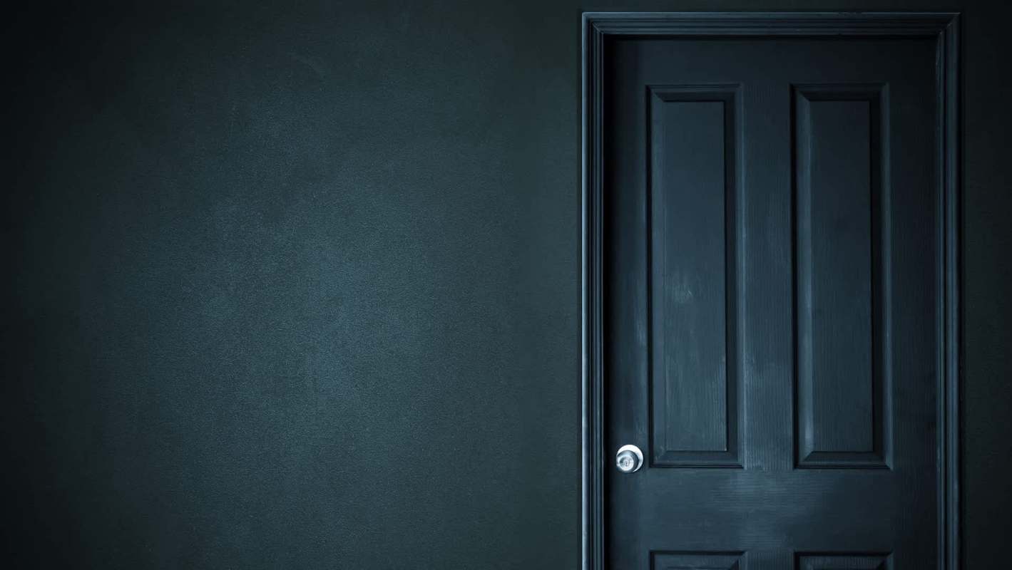 A dark door on a textured wall.