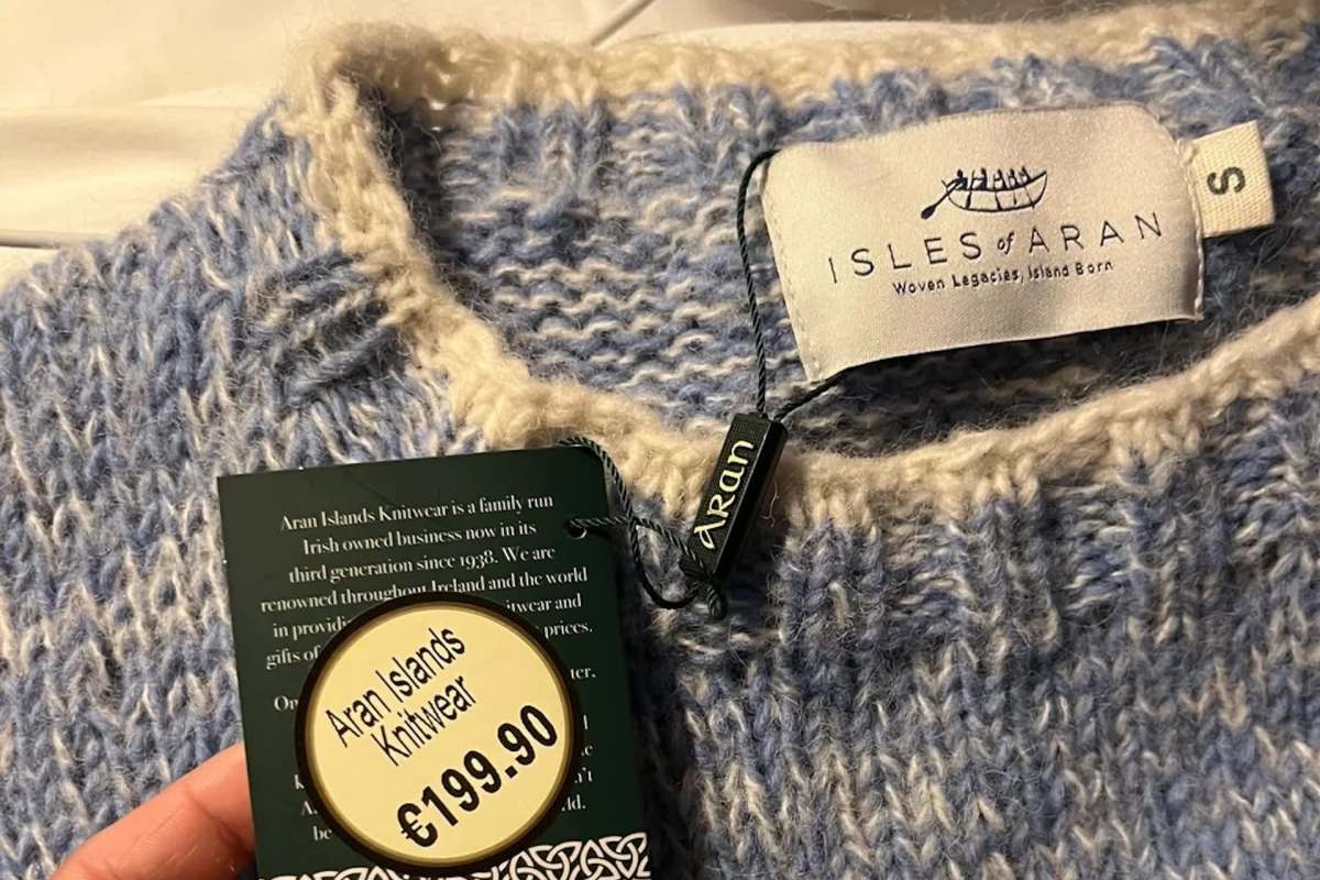 A blue and cream sweater with a price tag reading €199.90 and branding for Aran Islands Knitwear.
