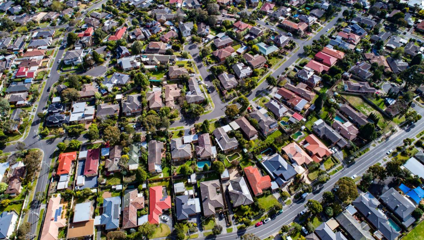 An aerial view of a residential neighborhood with various houses and tree-lined streets.