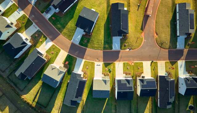 Aerial view of a suburban neighborhood with houses and a curved road.
