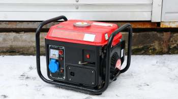 A red and black portable generator sitting on a snowy surface.